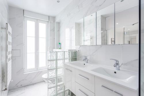 une salle de bain blanche avec un lavabo et un miroir dans l'établissement 180 Suite Eden, Luxury APT at Sacré Coeur, à Paris