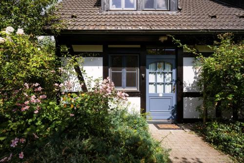 uma casa com uma porta azul e alguns arbustos em 4-Raum Apartment bis 6 Pers 21 em Rankwitz