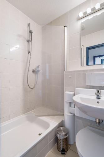 baño blanco con bañera, lavabo y aseo en 3-Raum Familienapartment bis 4 Pers 53 en Rankwitz