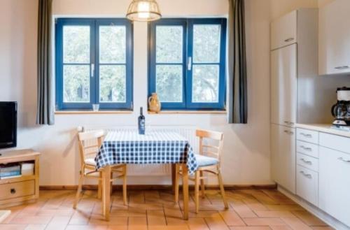 2-Raum Apartment bis 4 Pers 32 في Rankwitz: مطبخ مع طاولة وكراسي ونوافذ زرقاء