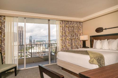 a hotel room with a bed and a balcony at Wyndham Vacation Resorts Royal Garden at Waikiki in Honolulu