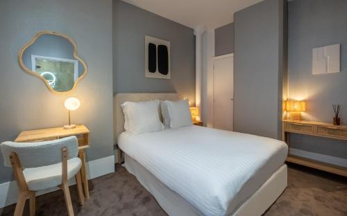 um quarto com uma cama, um espelho e uma cadeira em Makom Pereire em Paris