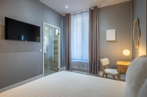 a bedroom with a bed with a television and a desk at Makom Pereire in Paris