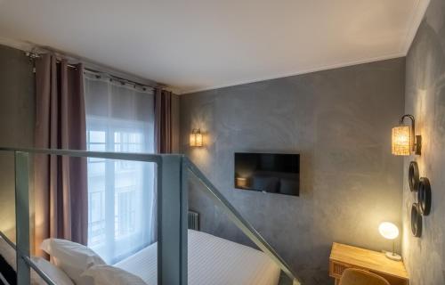 a room with a balcony with a bed and a television at Makom Pereire in Paris