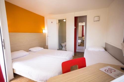 una camera d'albergo con due letti e un tavolo di Première Classe Cherbourg - Tourlaville a Cherbourg en Cotentin