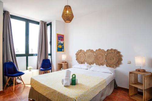 a bedroom with a bed and two blue chairs at Hotel Doña Matilde in Estepona