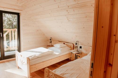 sypialnia z 2 łóżkami w drewnianym pokoju w obiekcie Babiogórska Chata - dom z bali z jacuzzi i sauną w Zawoi