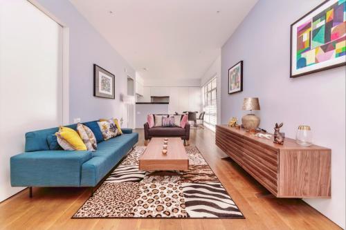 sala de estar con sofá azul y mesa en Interior-Designer Apartment with 2 TERRACES en Londres