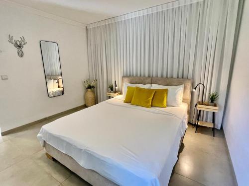 een slaapkamer met een groot wit bed met gele kussens bij Orhan Havaya in Sheʼar Yashuv
