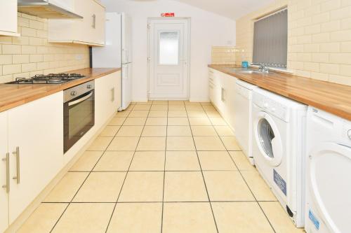 uma cozinha com uma máquina de lavar e secar roupa num piso de azulejo em Townhouse @ 115 Walthall Street Crewe em Crewe