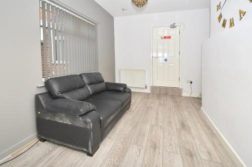 um sofá de couro preto sentado numa sala de estar em Townhouse @ 115 Walthall Street Crewe em Crewe