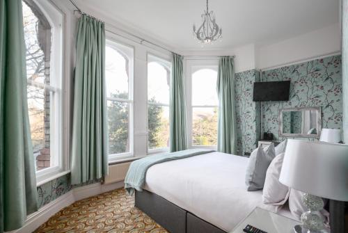 a bedroom with a bed with green curtains and windows at Sefton Park Hotel in Liverpool
