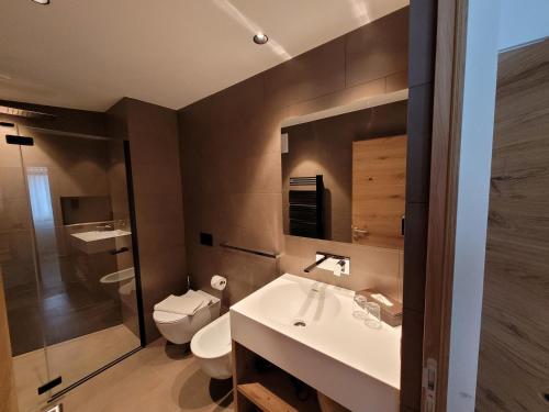 a bathroom with a sink and a toilet and a mirror at Apartments Stlarida in Ortisei