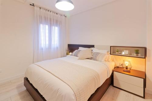 ein weißes Schlafzimmer mit einem großen Bett und einem Fenster in der Unterkunft Apartamento PLAYA12 in Gijón