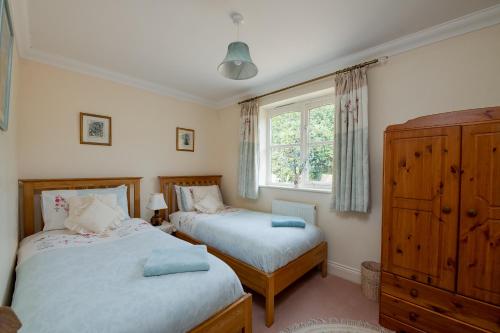1 dormitorio con 2 camas y ventana en Oak Tree Cottage, Charming, Rural New Forest Home, en Boldre