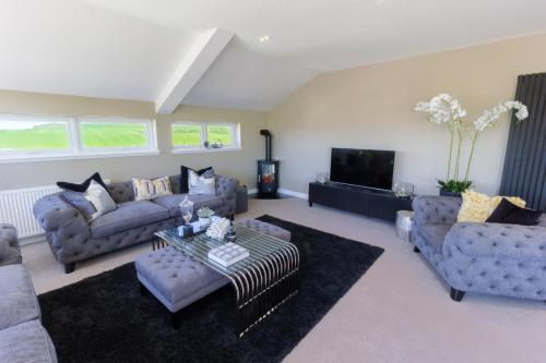 a living room with couches and a tv at Arran View Apartment at Heads of Ayr in Ayr