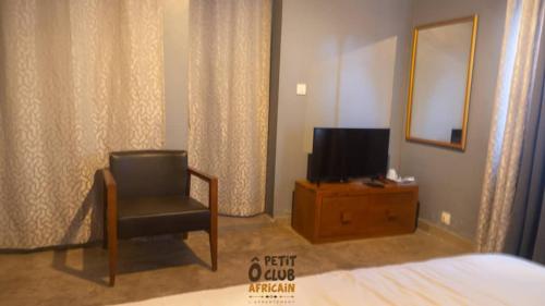 - une chambre avec une chaise et une télévision sur une commode dans l'établissement O Petit Club Africain Dakar, à Dakar