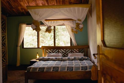 アルーシャにあるSanna Eco Lodgeのベッドルーム1室(天蓋付きベッド1台、窓付)