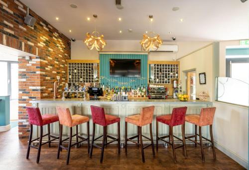 a kitchen with a bar with red bar stools at THE INN Hotel Bar and Restaurant in Saint Helier Jersey