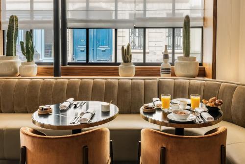 巴黎的住宿－Pavillon Faubourg Saint-Germain & Spa，沙发上两张桌子,上面摆放着食物和饮料