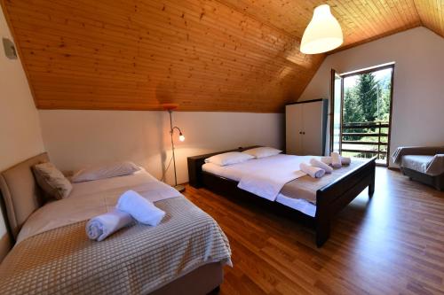 two beds in a room with wooden ceilings at Mate i Jaga in Saborsko