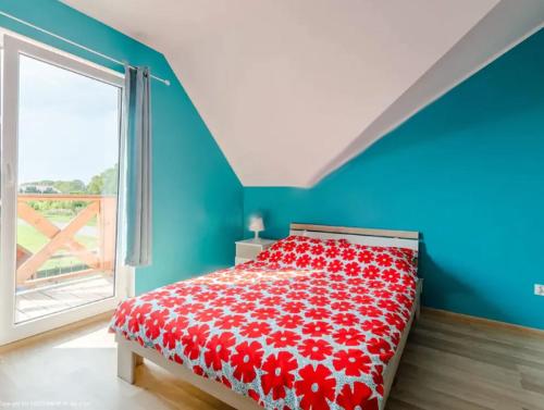 a bedroom with a bed with a red bedspread with a window at Domki wczasowe "Anna" - dom wakacyjny na wyłączność 75 m2 in Mielenko