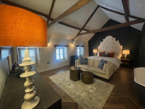 a bedroom with a bed and a couch and a lamp at The Hideaway in Saint Brides Major