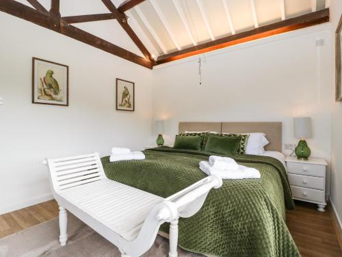 a white bedroom with a green bed and a white bench at The Old Kennels in Sidmouth
