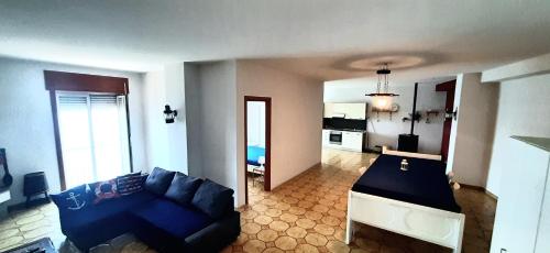 uma sala de estar com um sofá azul e uma cozinha em Castello Apartment em Bacoli