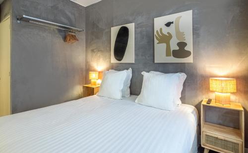 a bedroom with a bed with white sheets and two lamps at Makom Pereire in Paris