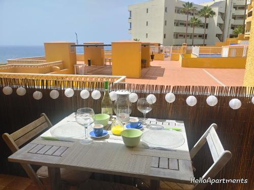 a table with plates and glasses on a balcony at Arena Beach by HelloApartments in Puerto de Santiago