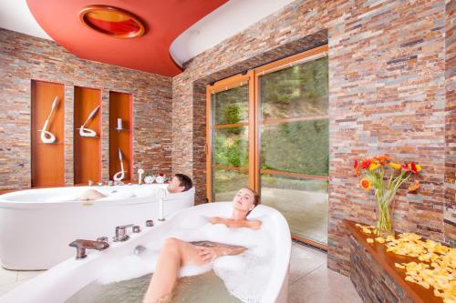 a man sitting in a bath tub in a bathroom at Hotel Lázně Kostelec in Zlín