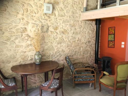 una mesa y sillas en una habitación con una pared de piedra en Chez Marie et Jean nature calme terrasse parking en Pujols-sur-Ciron