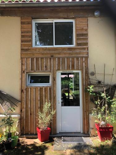 Casa de madera con puerta blanca y ventanas en Chez Marie et Jean nature calme terrasse parking en Pujols-sur-Ciron