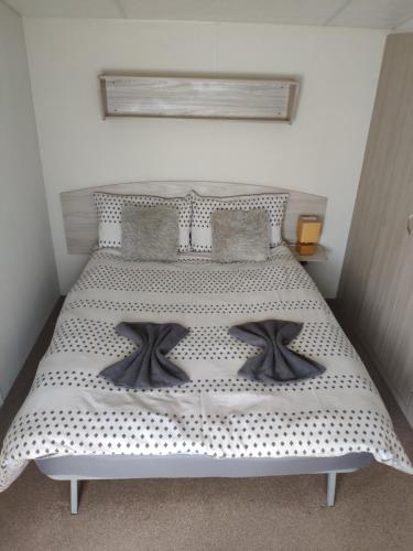 a bedroom with a bed with four pillows at Lovely Static 6 Bed Caravan at Billing Aquadrome in Great Billing