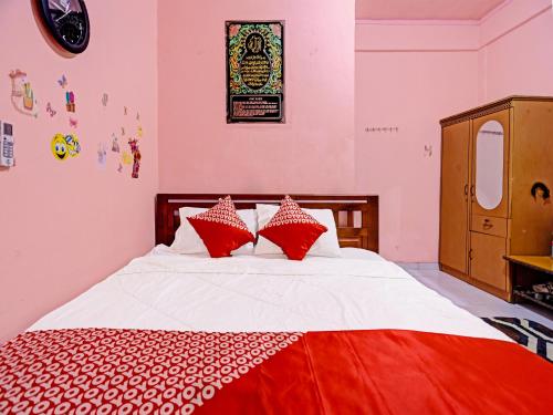 Schlafzimmer mit einem Bett mit roten und weißen Kissen in der Unterkunft OYO 91428 Duta Stay in Tanjung Pinang 
