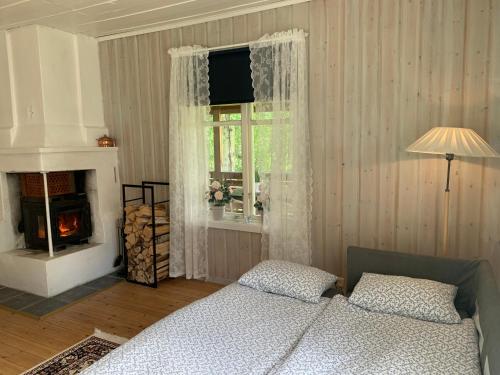 a bedroom with a bed and a window with a fireplace at Bogärdan, cozy cabin by the Luleå River in Harads