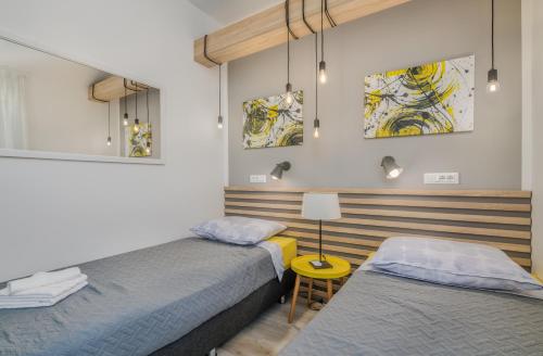 dwa łóżka w małym pokoju z lampą i obrazami w obiekcie Apartment Sunshine w mieście Klimno