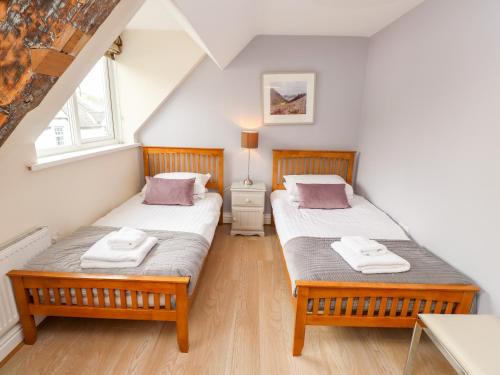 two twin beds in a room with two windows at Two The Chapel - Staveley in Staveley