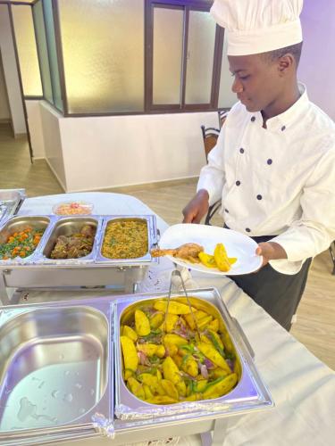 a chef is holding a plate of food at Monrovia Guest House in Nakuru