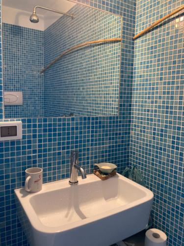 a blue tiled bathroom with a sink and a mirror at Casa Nica in Ustica