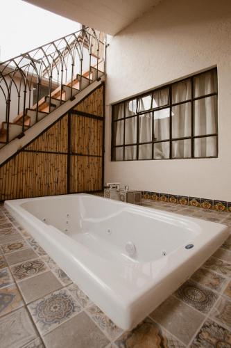 a large white tub in a bathroom with a tile floor at Hotel Casa Guivá in Oaxaca City