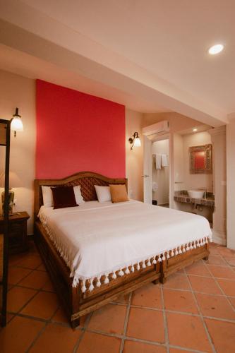 a bedroom with a large bed with a red wall at Hotel Casa Guivá in Oaxaca City