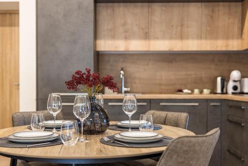 a table with wine glasses and a vase with red flowers at Luxury apartment DOLCE VITA in Palanga