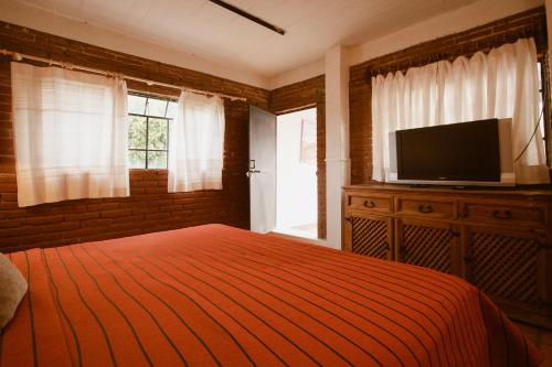 a bedroom with a bed and a flat screen tv at Hotel Casa Guivá in Oaxaca City