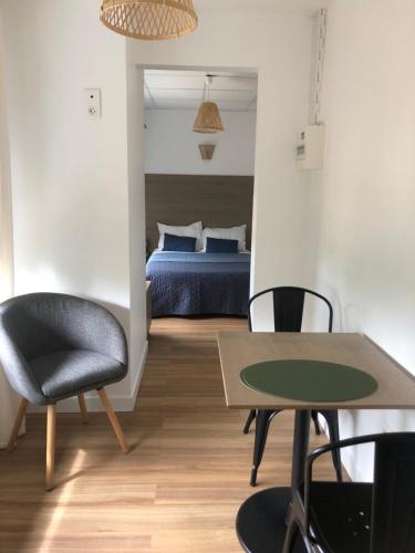 1 dormitorio con 1 cama, mesa y sillas en Cosyade Parking privé gratuit, en Bourbourg