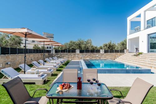 eine Terrasse mit einem Tisch, Stühlen und einem Pool in der Unterkunft Boheme Villa in Zakynthos