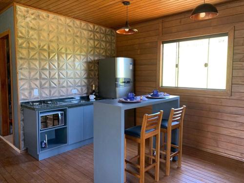 a kitchen with a counter with chairs and a refrigerator at Recanto- Pousada Cachoeira da Neve in Urubici
