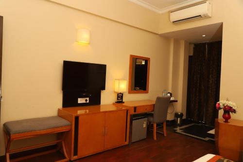 a hotel room with a desk and a television at L'ELEGANT Hotel & Banquet in Ghaziabad