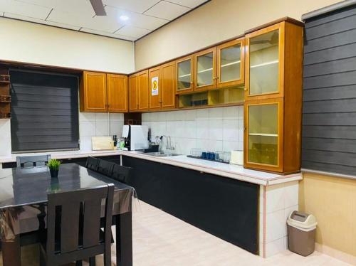 a large kitchen with wooden cabinets and a table at ALOR SENARI HOMESTAY PRIVATE POOL in Pantai Cenang